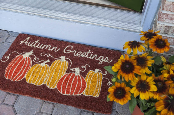 Coir doormat outside door with pumpkins illustration and Autumn Greetings text